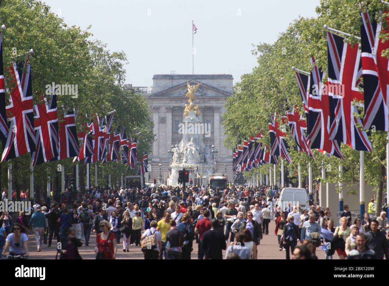 People flood The Mall on a summer day as the road is lined by British flags towards Buckingham Palace and is closed to traffic, in London, UK. Stock Photo