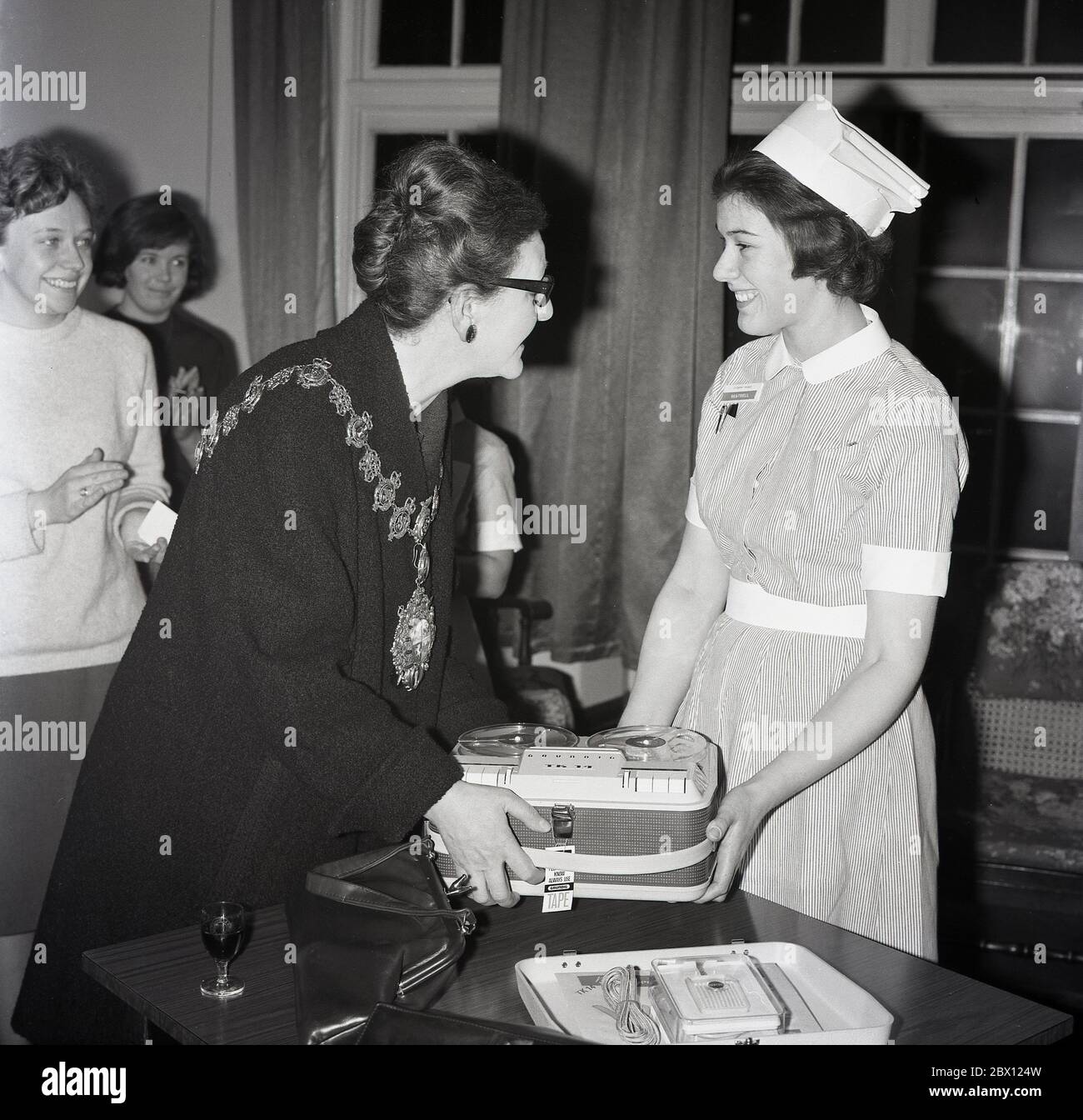 1960s, historical, 'Congratulations', at a prize giving, a young female nurse being presented with the latest audio technology, a portable reel to reel audio tape recorder by the Lady Mayoress of Lewisham, South London, England, UK. Stock Photo