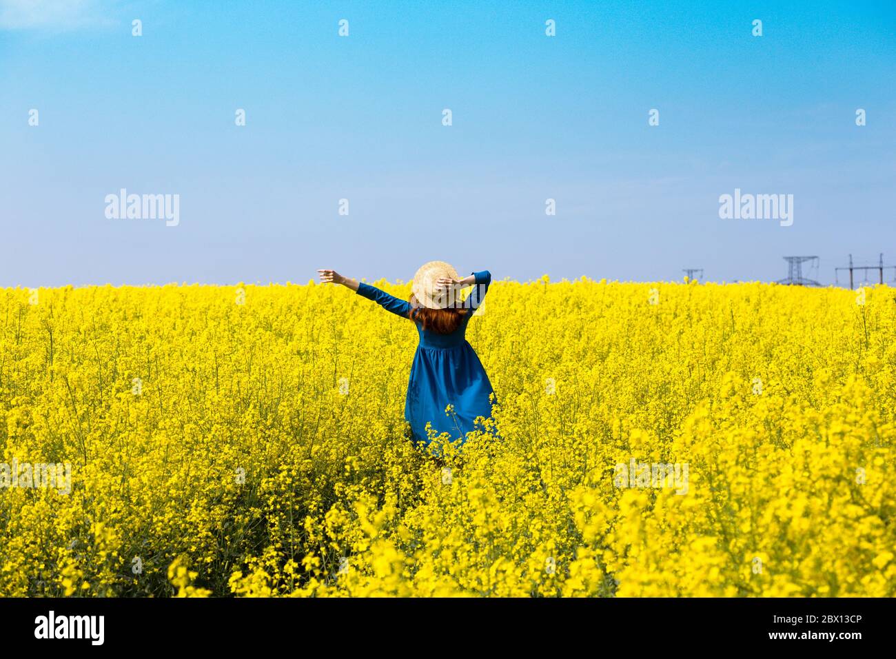 Happy girl in a hat walking in amazing field of yellow rapeseed in the ...