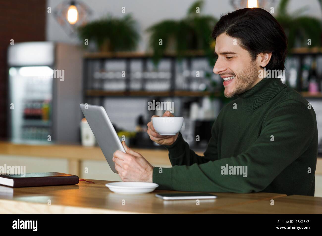 Cheerful man using digital tablet and drinking coffee Stock Photo
