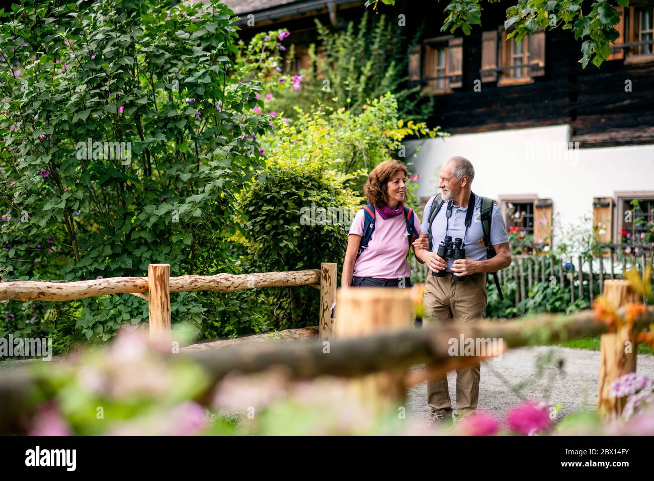 A senior pensioner couple with binoculars hiking, talking. Stock Photo