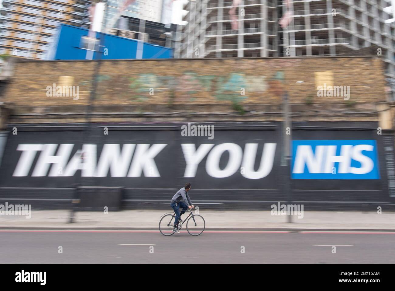 A cyclist rides past a 'thank you NHS' mural in Shoreditch, east London, following the introduction of measures to bring England out of lockdown. Stock Photo