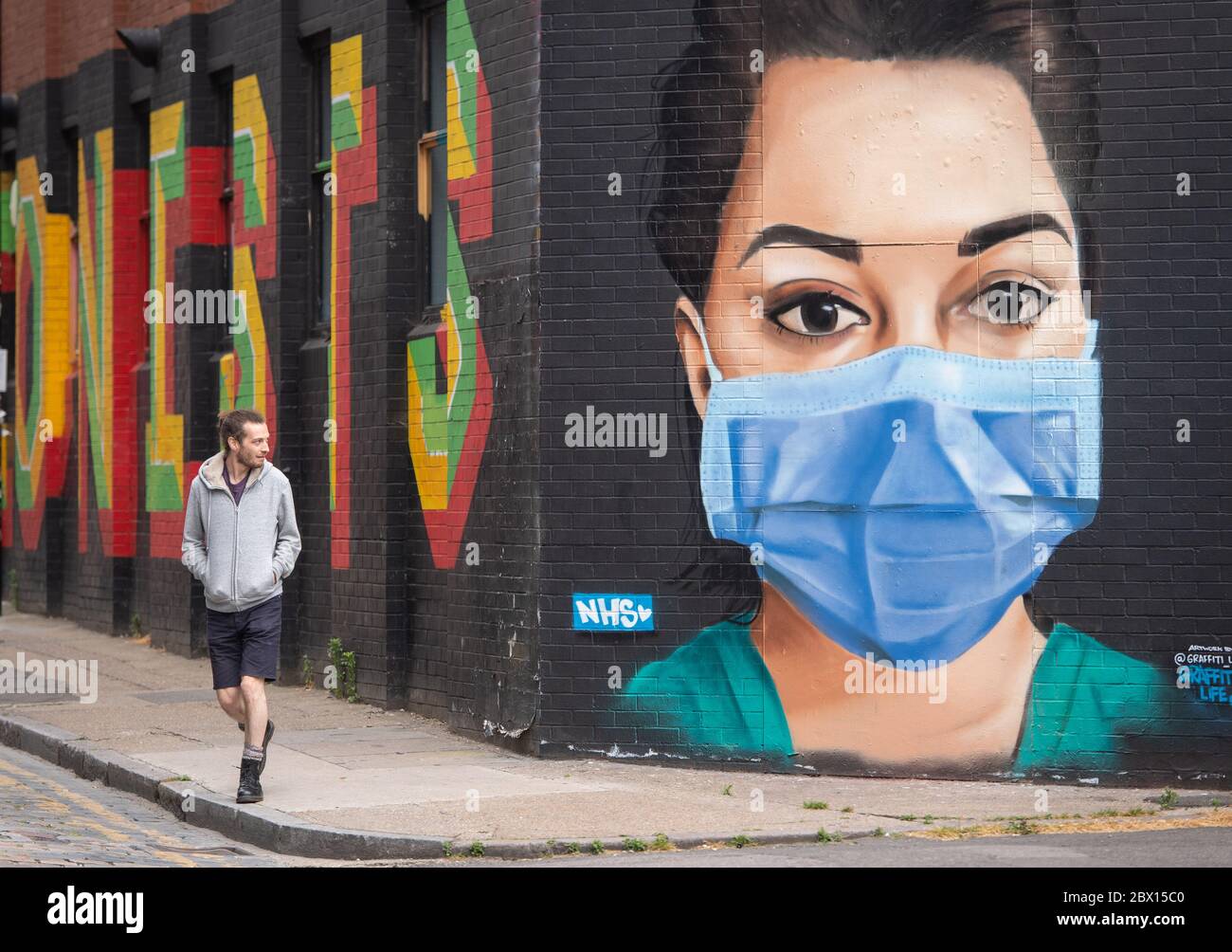 A man looks at a mural showing a nurse wearing personal protective