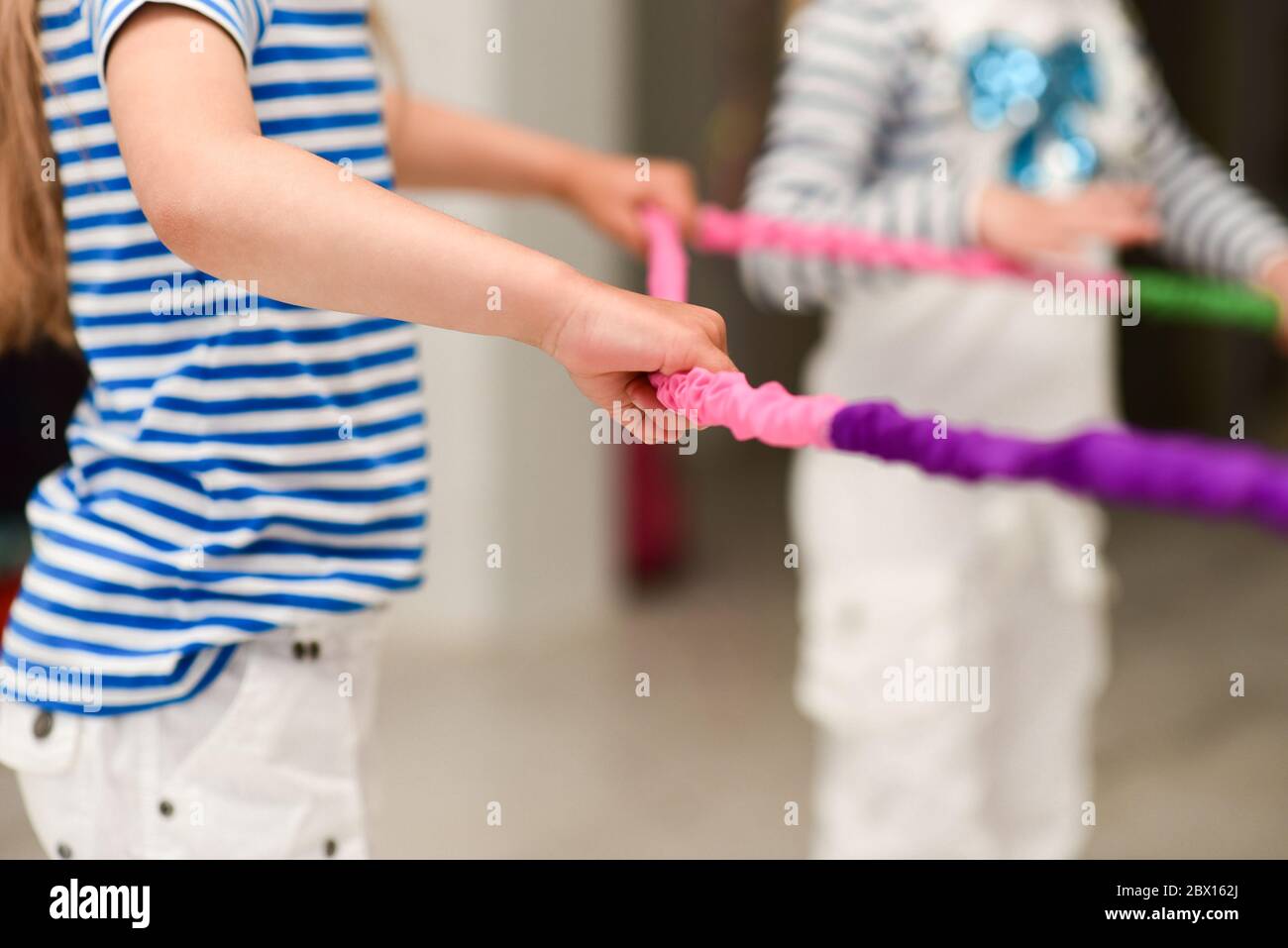 Children hands play at a party with a colored rope. Stock Photo