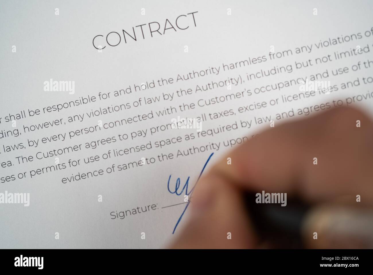Close up hand with pen on the signature line on a contract ready to be ...