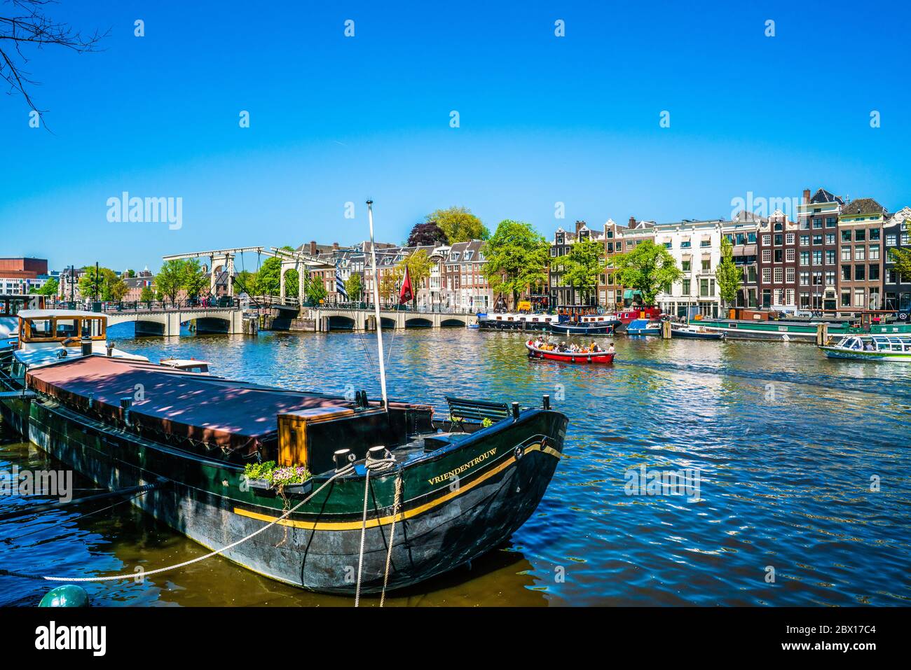 Amsterdam, May 7 2018 - view on the river Amstel filled with small boats and the Magere brug (skinny bridge) in the background on a summer day Stock Photo