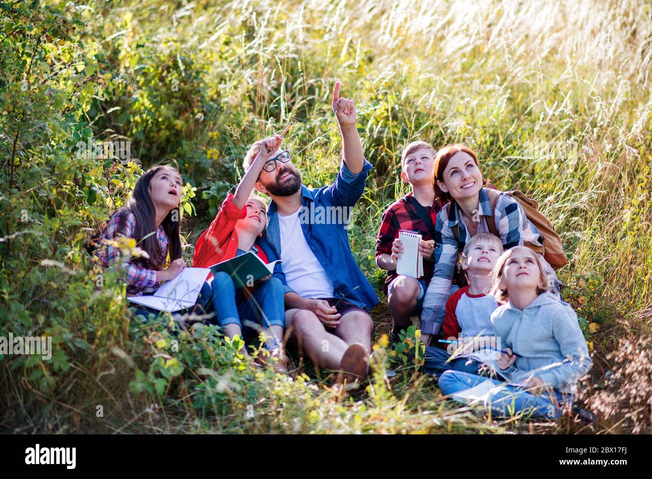 Group of school children with teacher on field trip in nature. Stock Photo