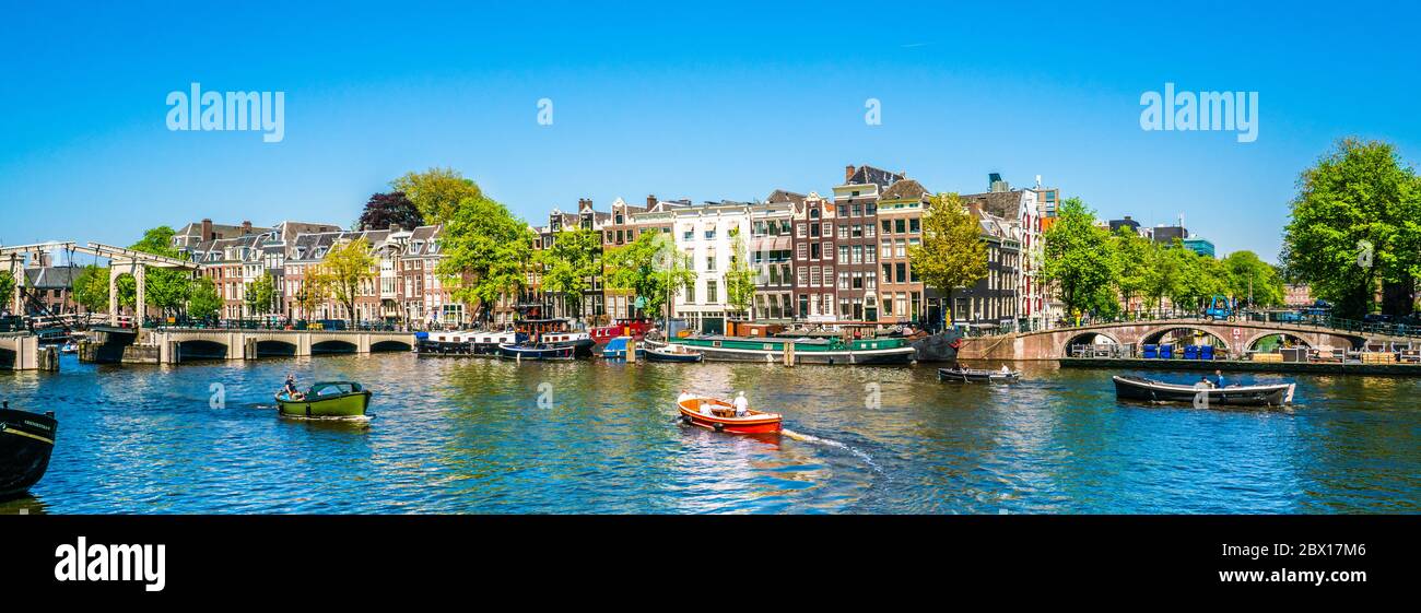 Amsterdam, May 7 2018 - view on the river Amstel filled with small boats and the Magere brug (skinny bridge) in the background on a summer day Stock Photo
