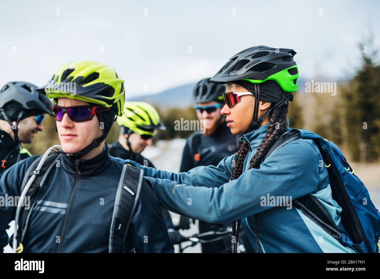 Group of mountain bikers standing on road outdoors in winter, talking. Stock Photo