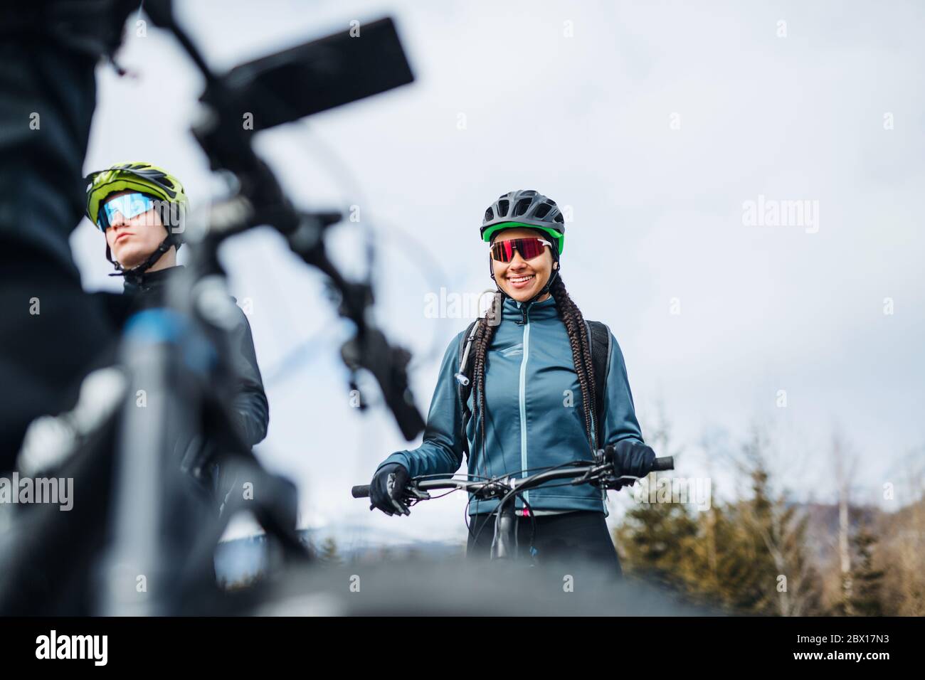 Group of mountain bikers standing on road outdoors in winter, talking