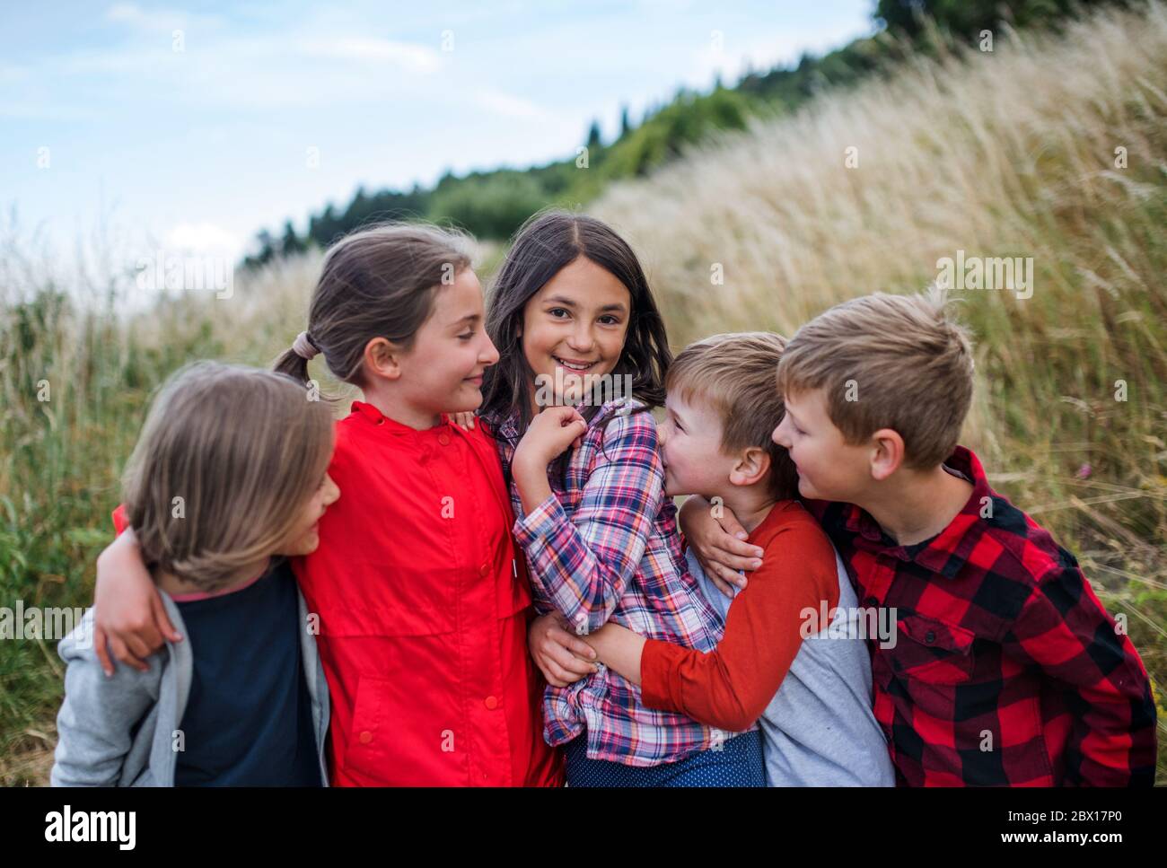 Group of school children standing on field trip in nature, playing. Stock Photo