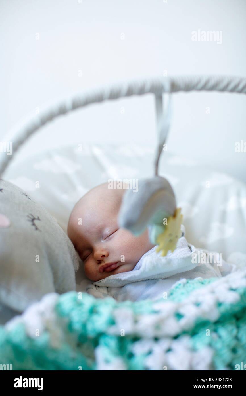 A newborn baby girl sleeping in a  baby bouncer.  Photo by Sam Mellish Stock Photo