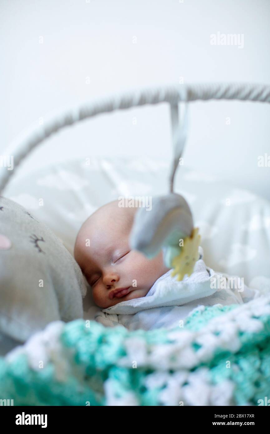 A newborn baby girl sleeping in a baby bouncer. Photo by Sam Mellish Stock Photo Alamy