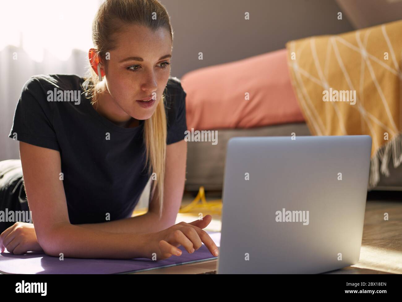 Young woman taking part in online fitness class in front of laptop. Stock Photo