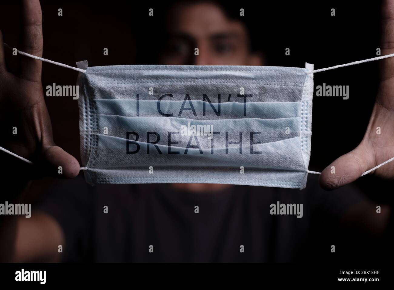 Young man holding medical mask with I Can't Breathe inscription on it. Cooncept of Protest about racial discrimination of Black People in U.S. America Stock Photo