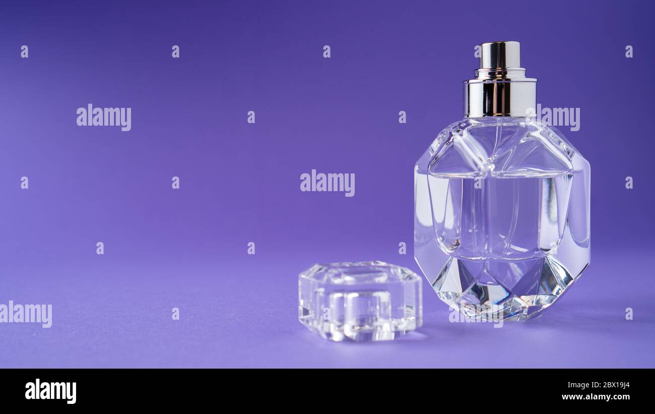 Fashion perfume in glass bottle on purple background. Diamond bottle shape. Transparent bottle. Crystal. Isolated Stock Photo