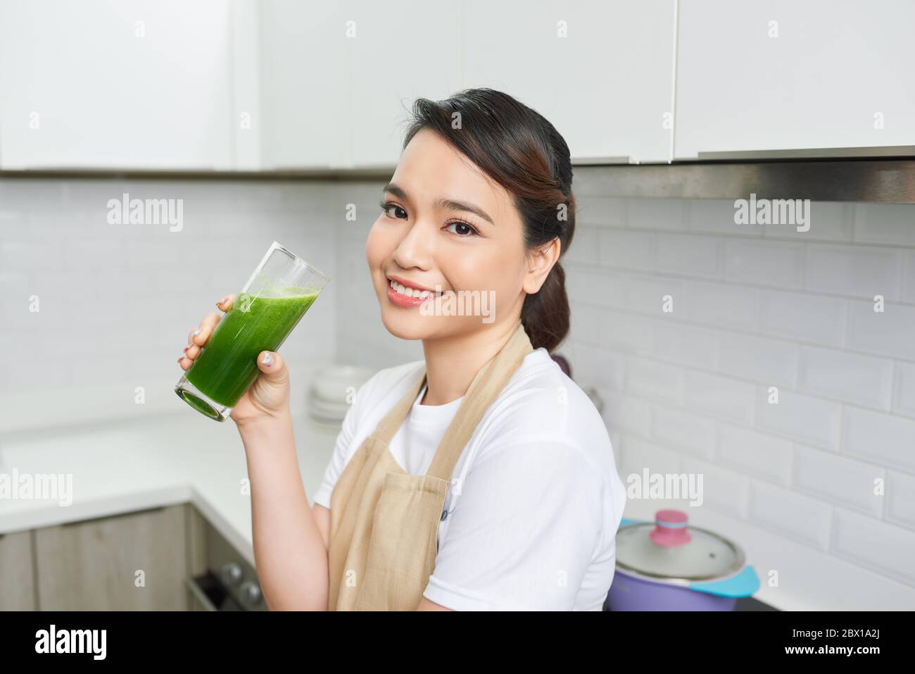Detox Concept. Close up portrait of asian girl holding glass with homemade green juice, looking aside at free space Stock Photo