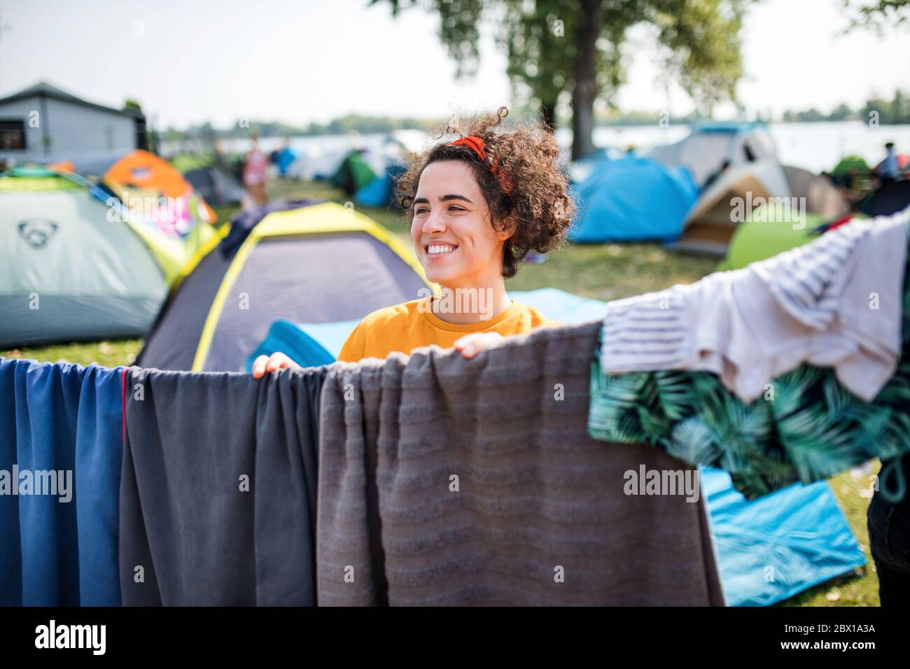 Young woman hanging towels at summer festival or camping holiday. Stock Photo