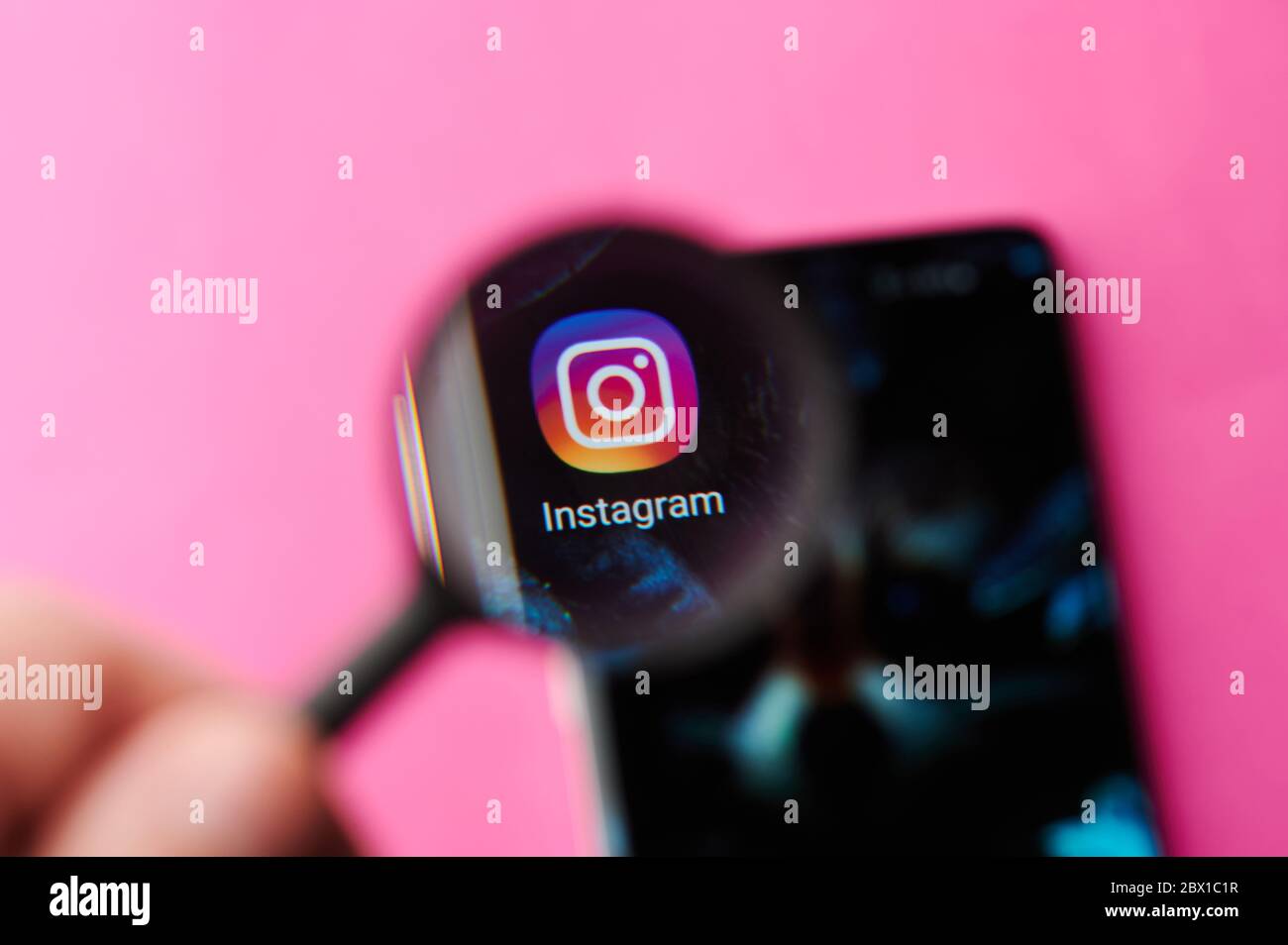 New-York , USA - June 4 , 2020: Browsing Instagram app on modern smartphone throw magnifier close up view Stock Photo