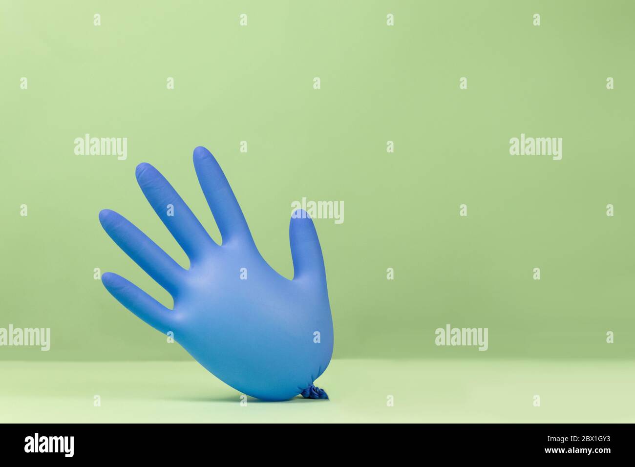 Latex inflated rubber glove inflated like balloons on a green background. Funny colorful and bright concept Stock Photo