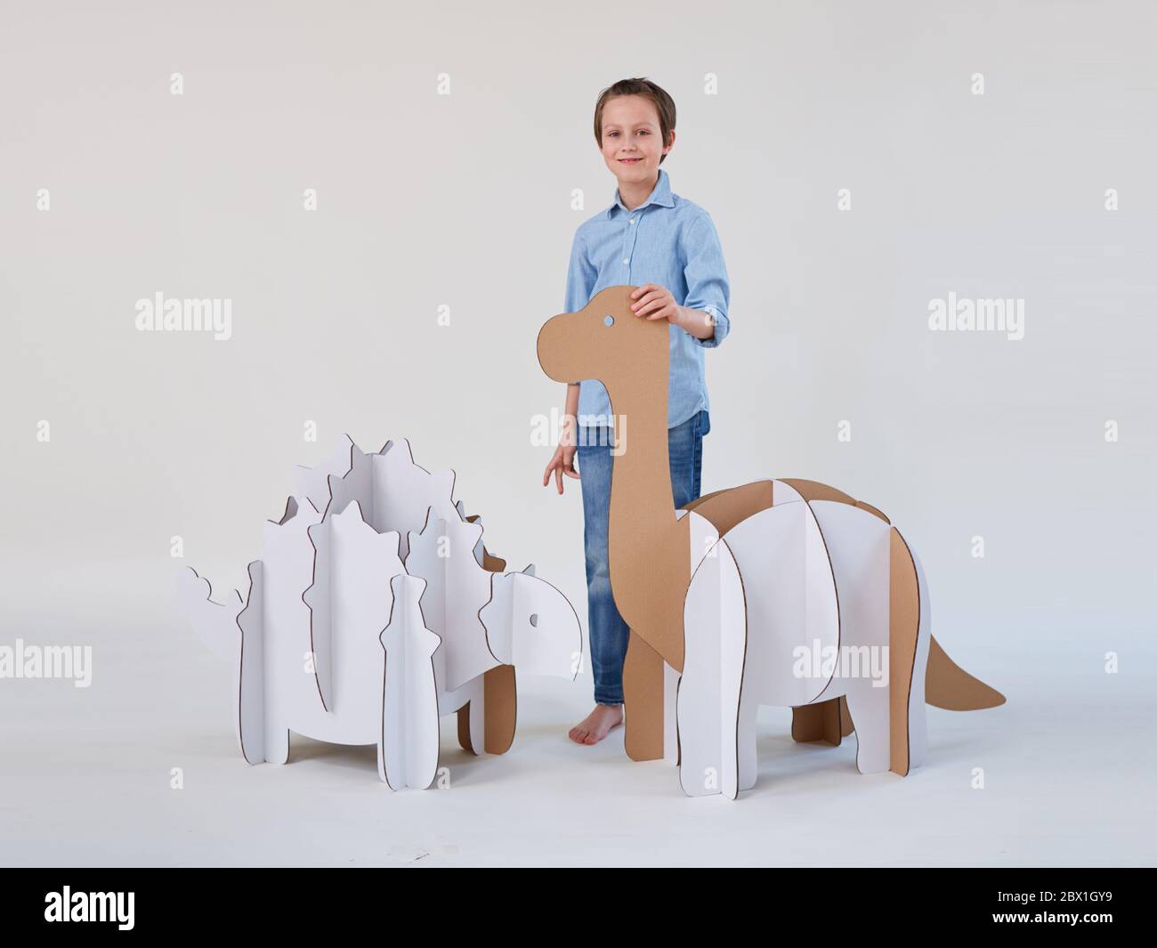 Little dreamer boy playing with a cardboard dinosaurs Brontosaurus and