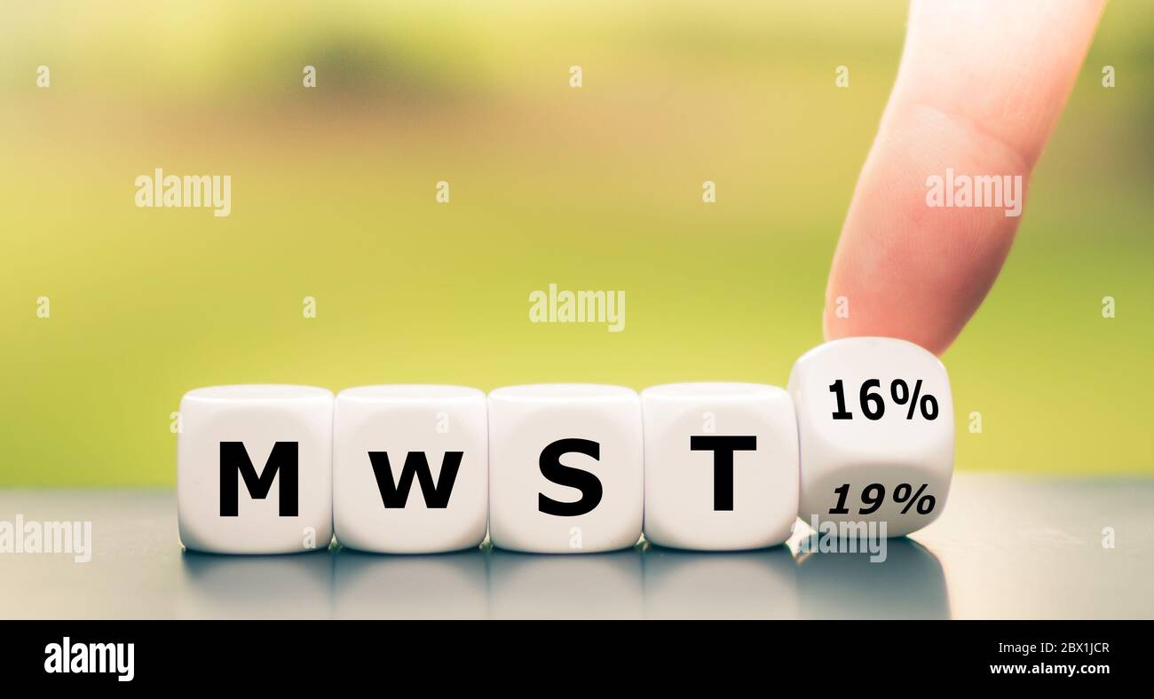 German stimulus packages after the corona crisis. Hand turns dice and changes the expression 'MwST 19%' ('value added tax 19%') to 'MwST 16%' ('value Stock Photo