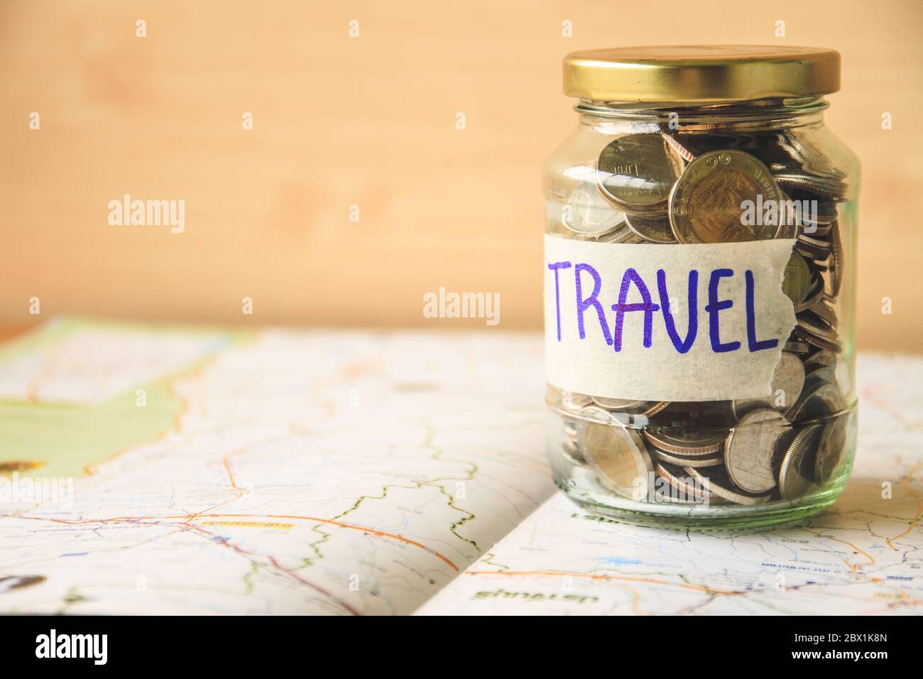 Coins in a glass jar on a map. Saving money for travel concept Stock Photo