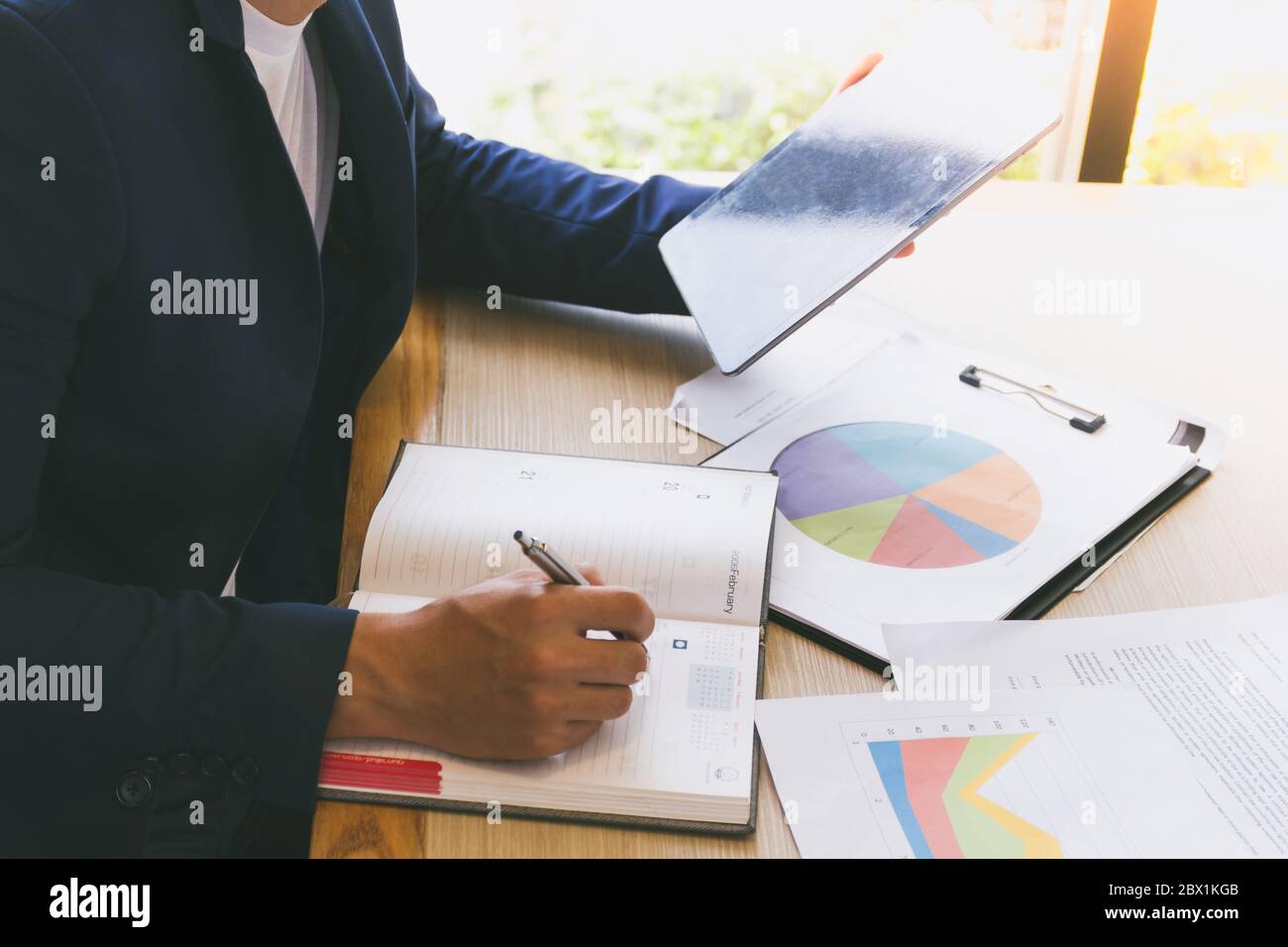 Businessman using tablet and analyzing investment charts on the desk ...