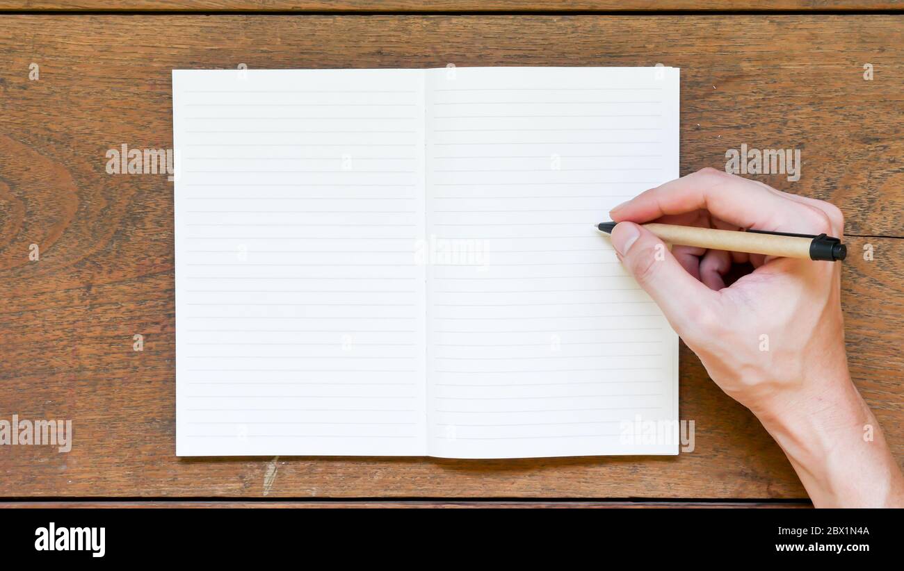 Man hands with pen writing on empty notepad over wooden table Stock ...