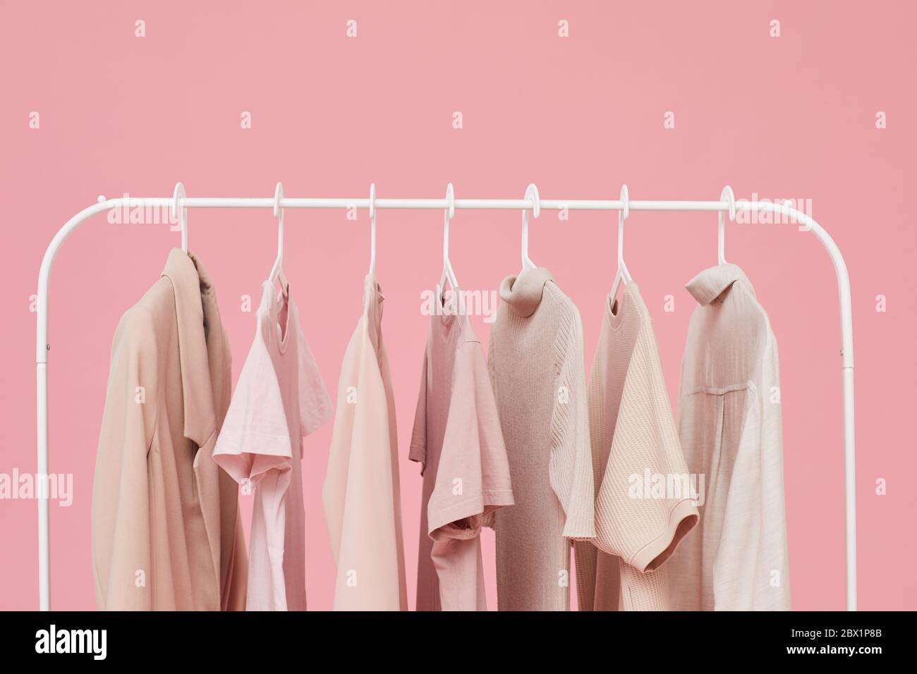 Image of clothes hanging on the rack isolated on pink background Stock