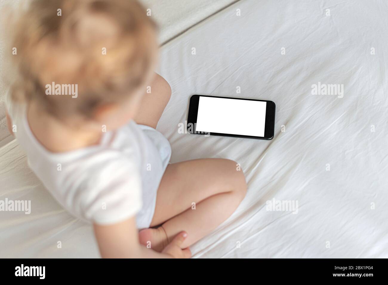 Little girl is watching something on smartphone. Stock Photo