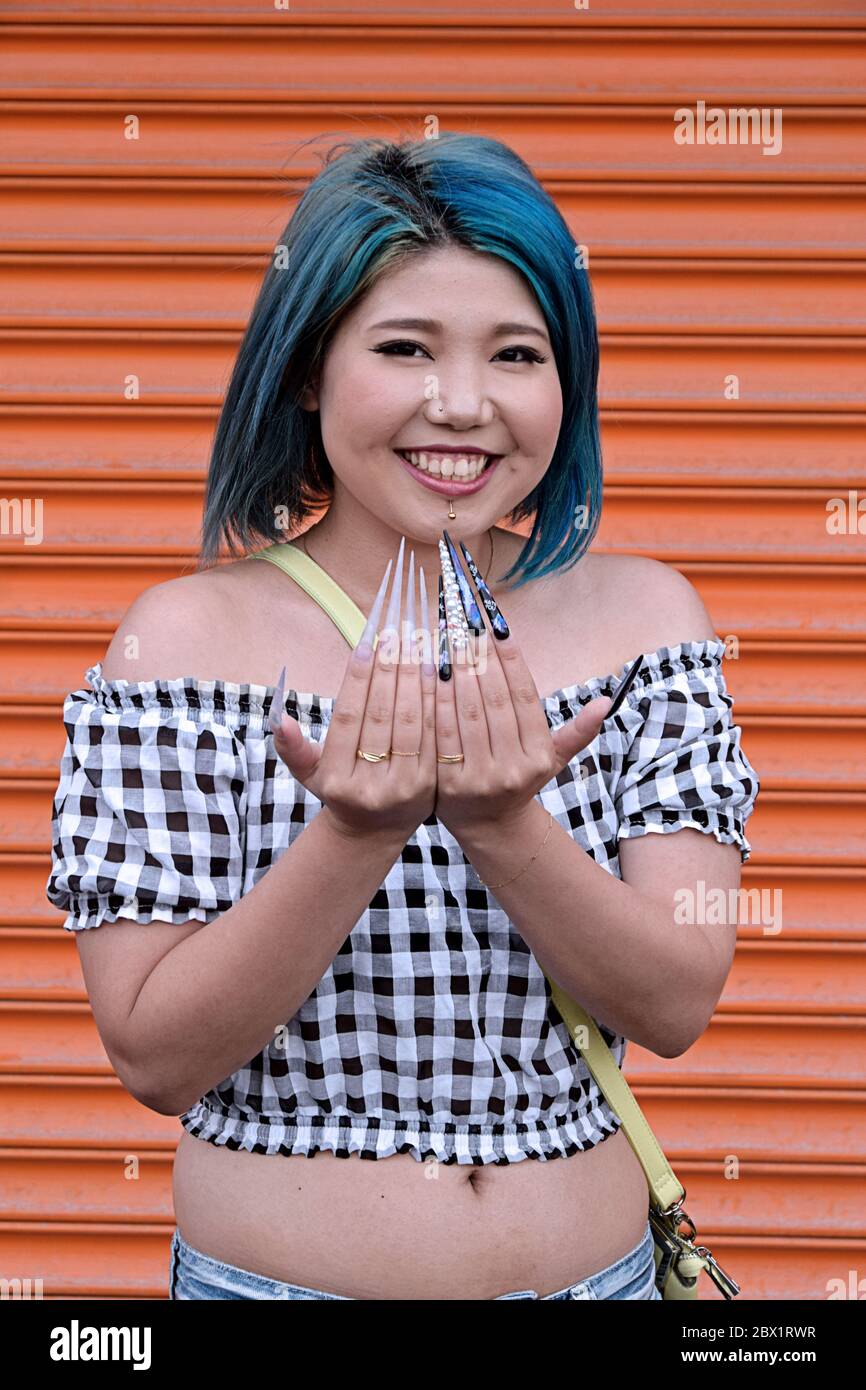 A young Japanese American woman with blue hair and exceptionally long fingernails at Coney Island, Brooklyn, New York. Stock Photo