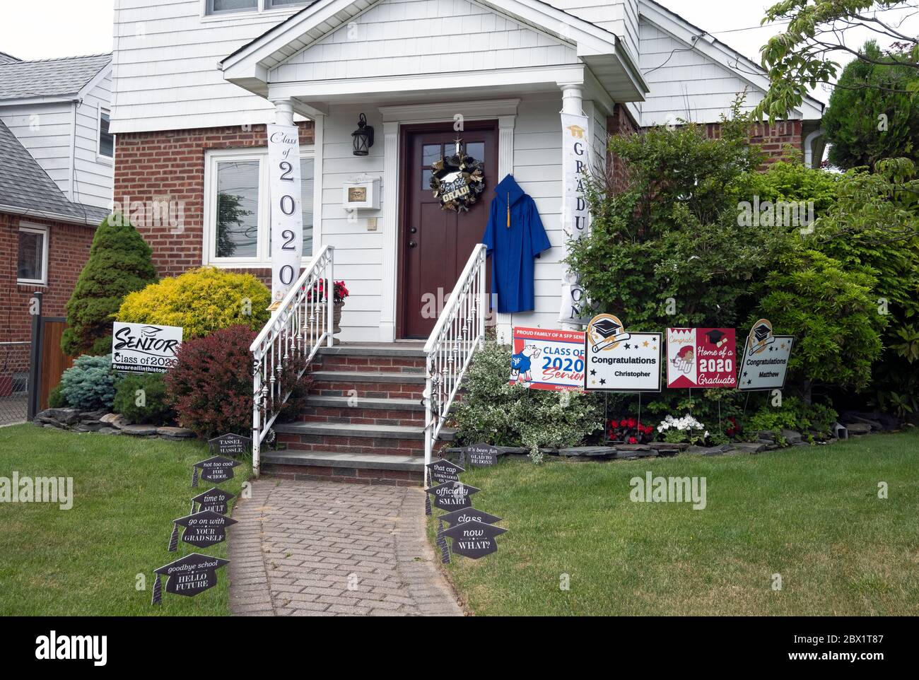 In lieu of an actual graduation, a family celebrates their graduates with congratulatory signs in their front yard. In Bayside, Queens, NYC. Stock Photo