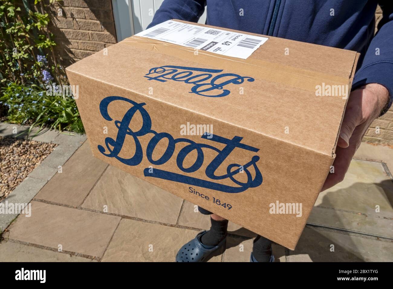 Close up of man carrying holding delivering Boots box internet parcel package home delivery shopping England UK United Kingdom GB Great Britain Stock Photo