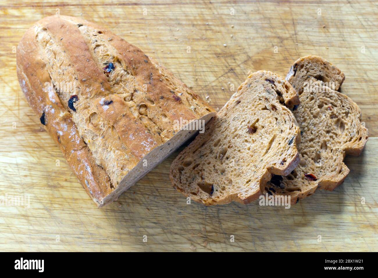 Mediterranean sun dried tomato and olive bread with a shallow depth of field on a cutting board with two sliced pieces and crumbs Stock Photo