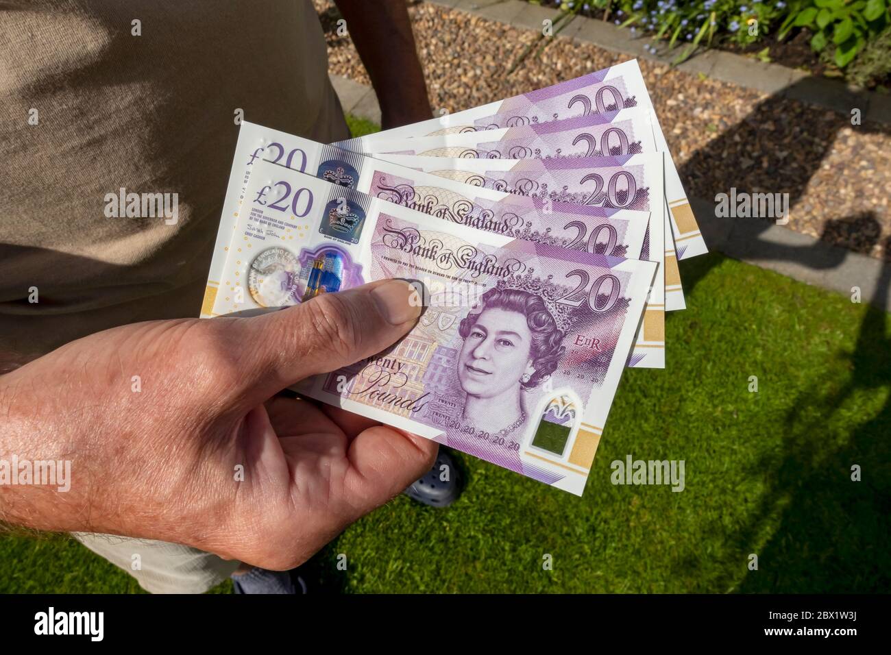 Close up of man person holding paying new £20 twenty pound banknotes notes cash money  England UK United Kingdom GB Great Britain Stock Photo
