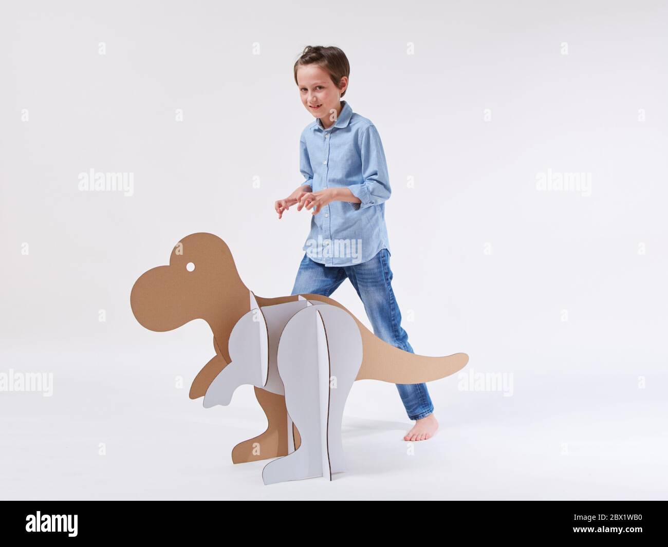 Little dreamer boy playing with a cardboard dinosaur Tyrannosaurus rex