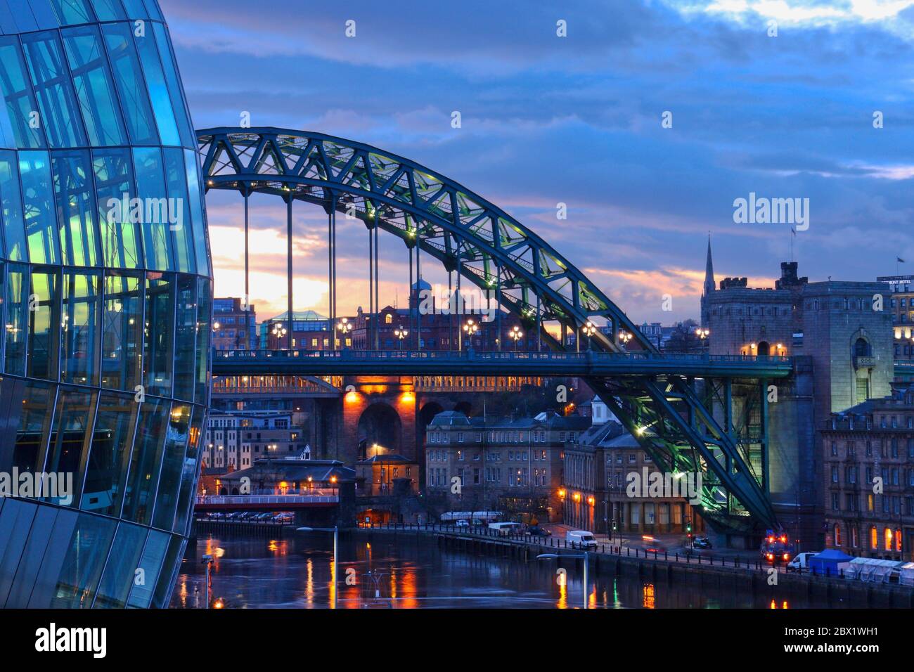 The arch of the Tyne Bridge  spanning the River Tyne joing Newcastle and Gateshead in Tyne and Wear taken at dusk with the Sage Centre glass windows i Stock Photo
