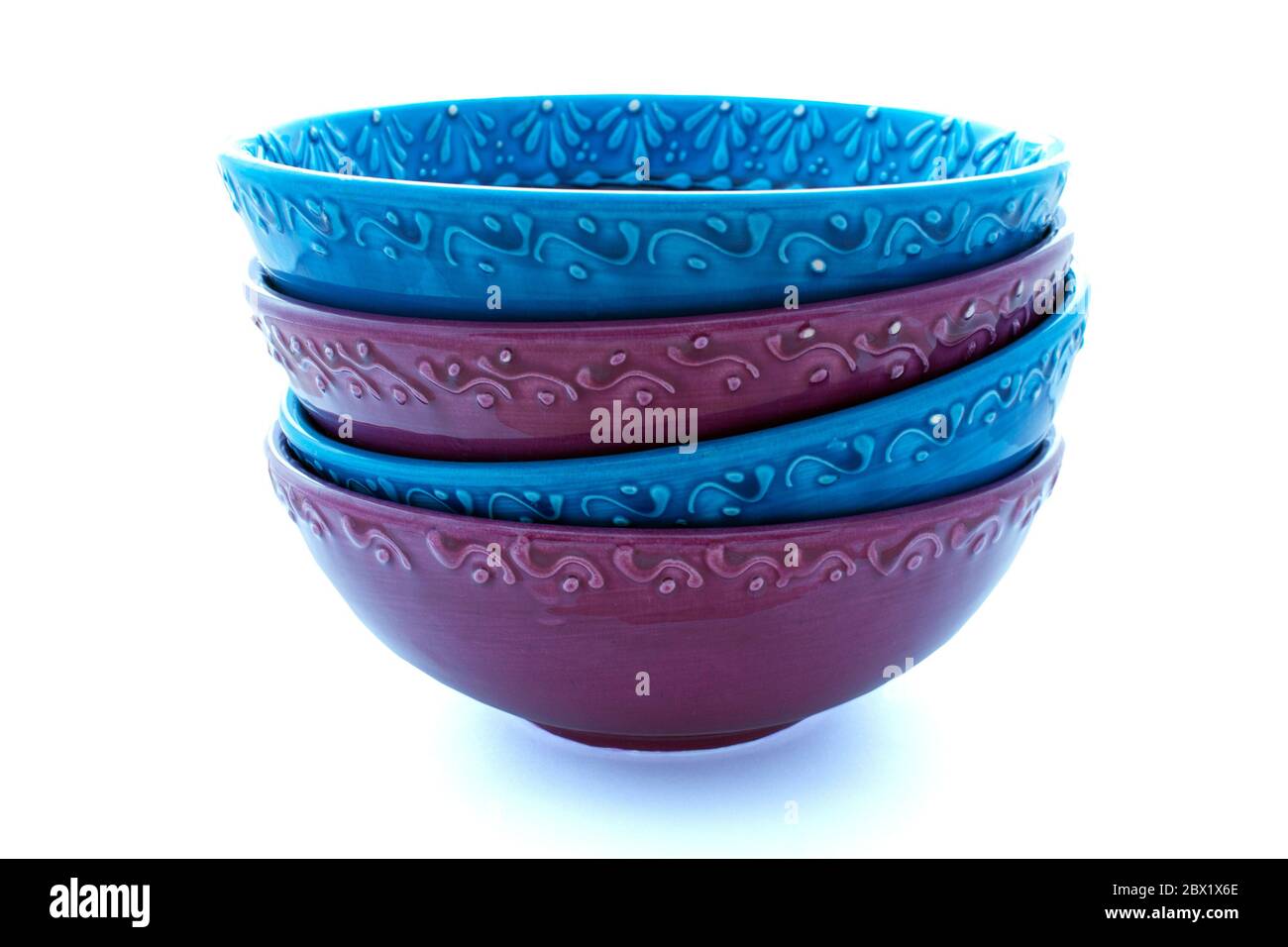 Four handmade blue and purple bowls stacked at angles Stock Photo
