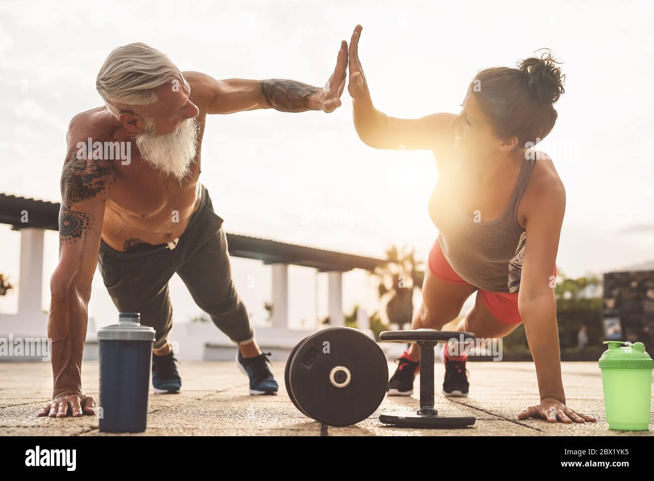 Fitness couple doing push ups exercise outdoor - Happy athletes making workout session at sunset outside Stock Photo