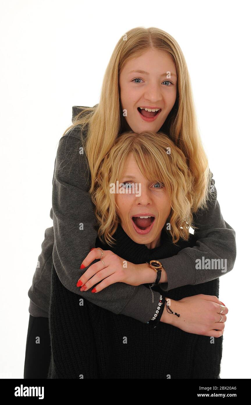 pretty blonde Mum and teenage girl cuddling and looking shocked ...