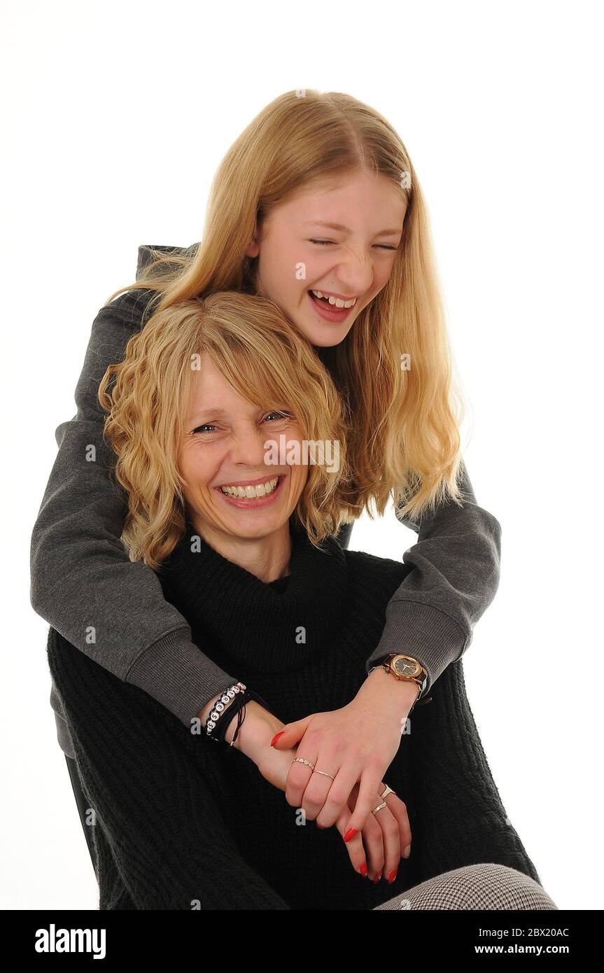 pretty blonde Mum and teenage girl cuddling and laughing, isolated on ...