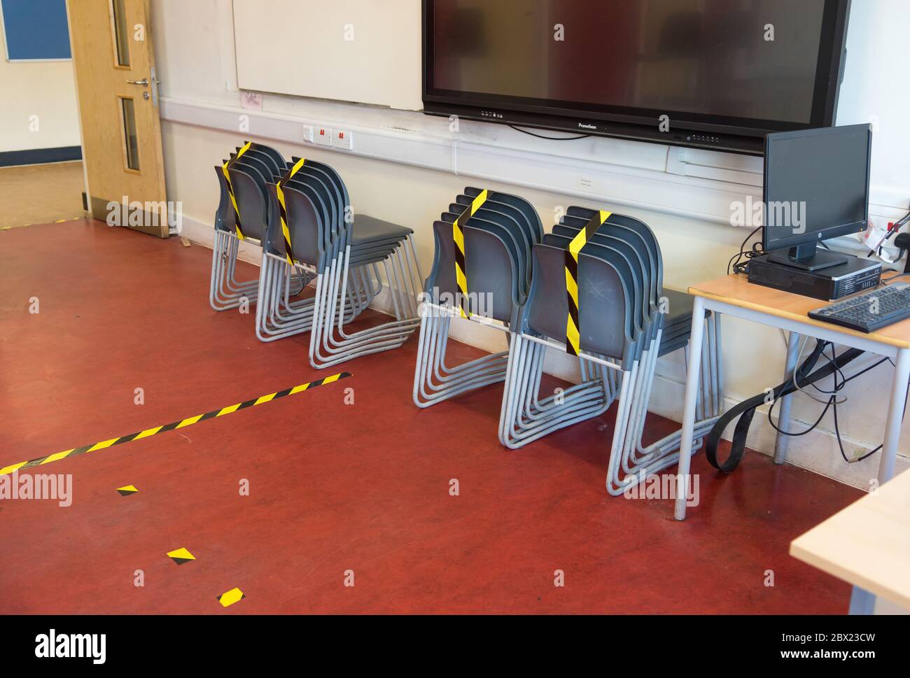 Social distancing measures in a school classroom with tape separating tables and chairs in response to the COVID-19 Coronavirus. Stock Photo