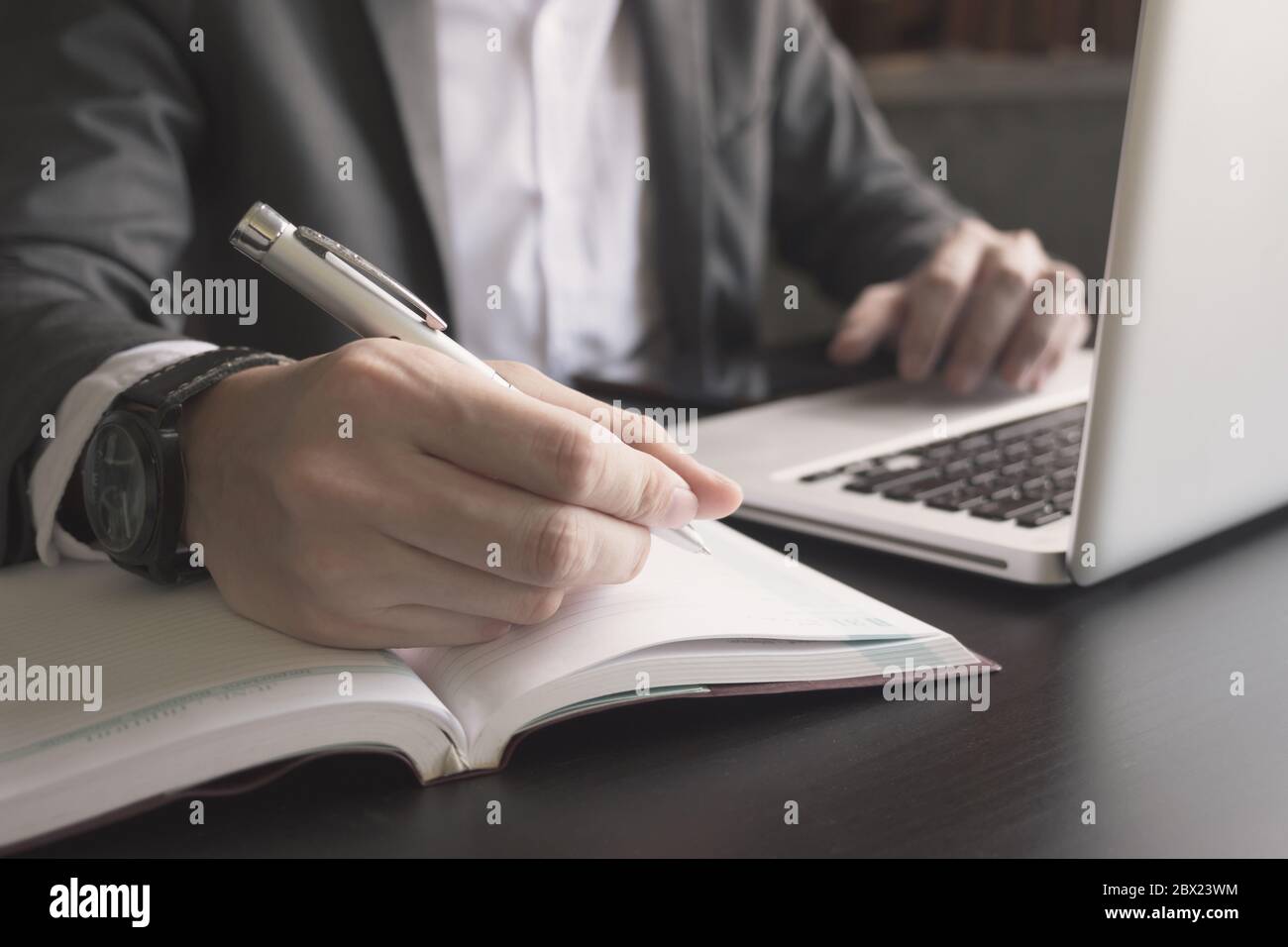 Close up of businessman writing note and using a laptop on the office ...