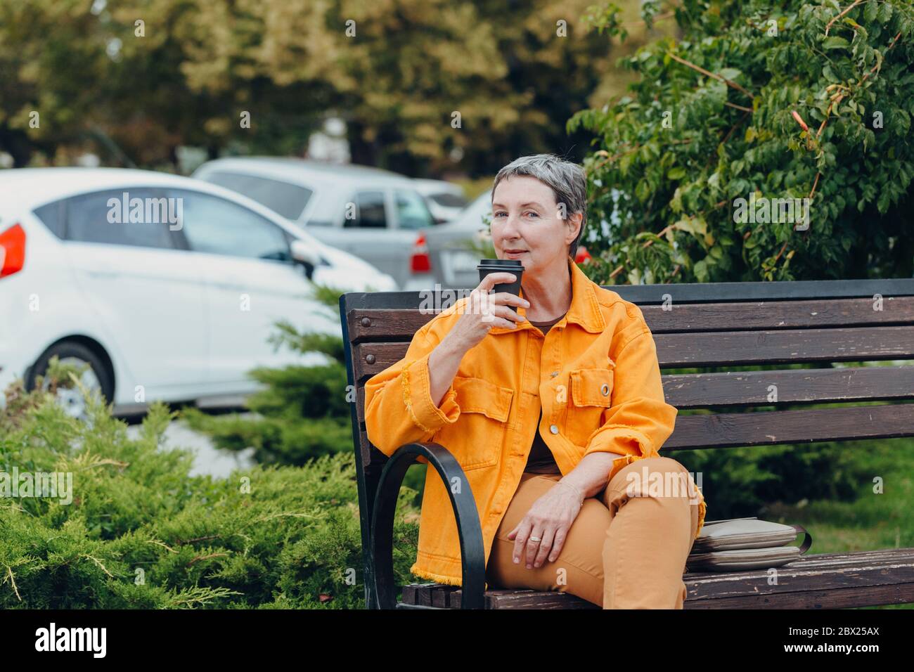 Happy stylish stylish fashionable senior woman dressed in the city streets with a glass of coffee in her hands. anti aging concept Stock Photo