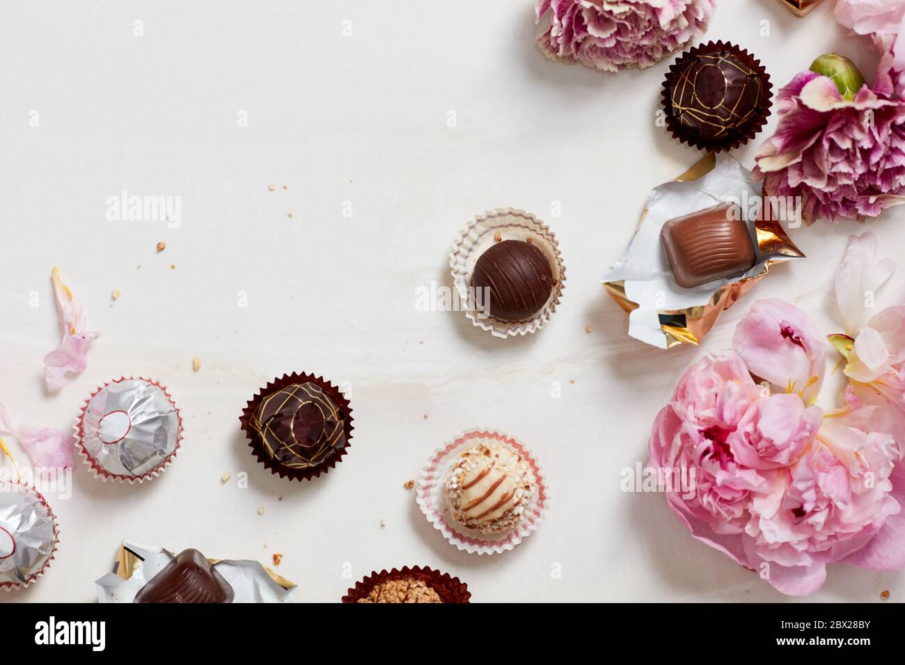 Still life of open chocolates and wrappers with flowers Stock Photo Alamy