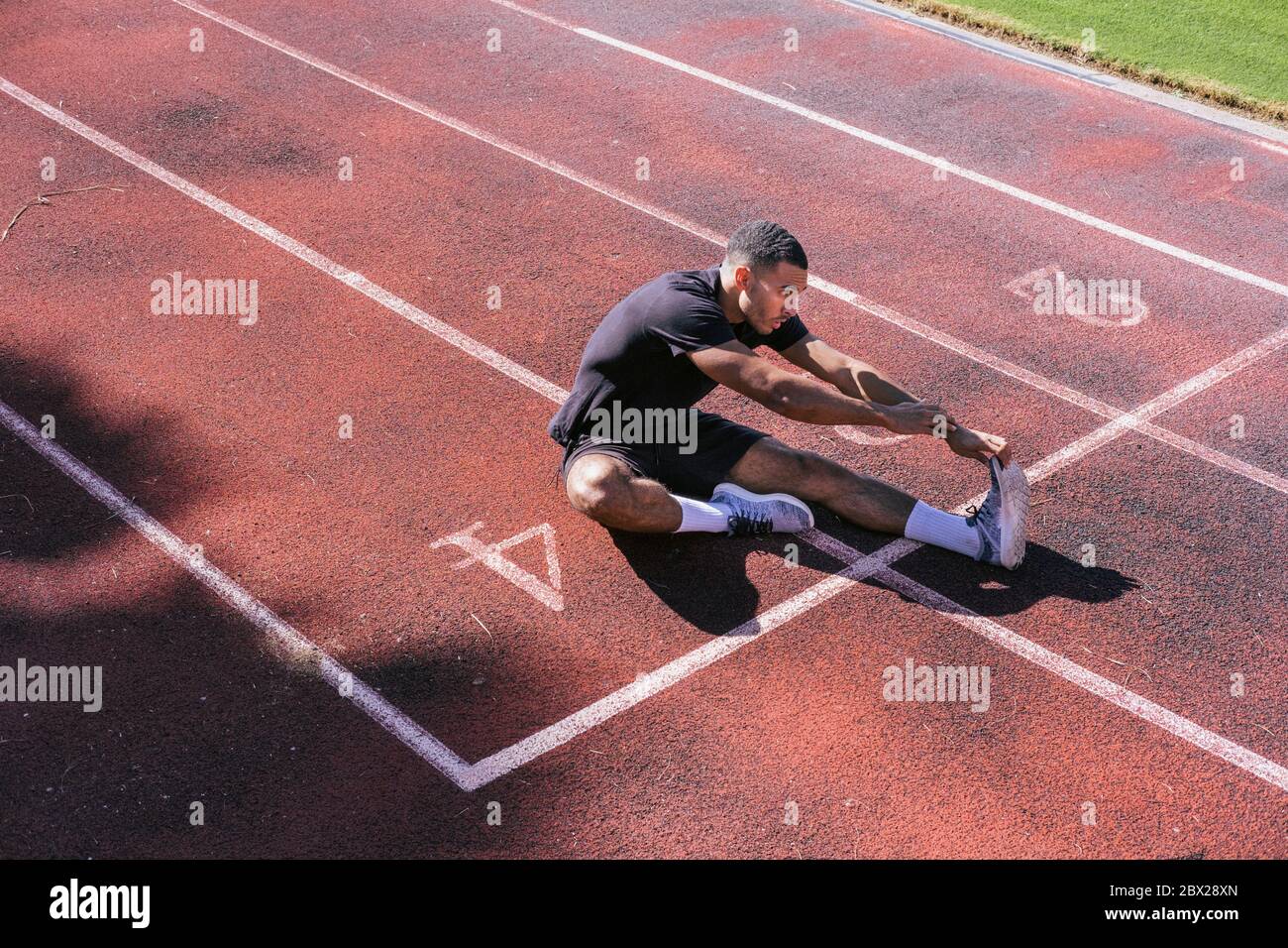 African American athlete stretching on running track Stock Photo
