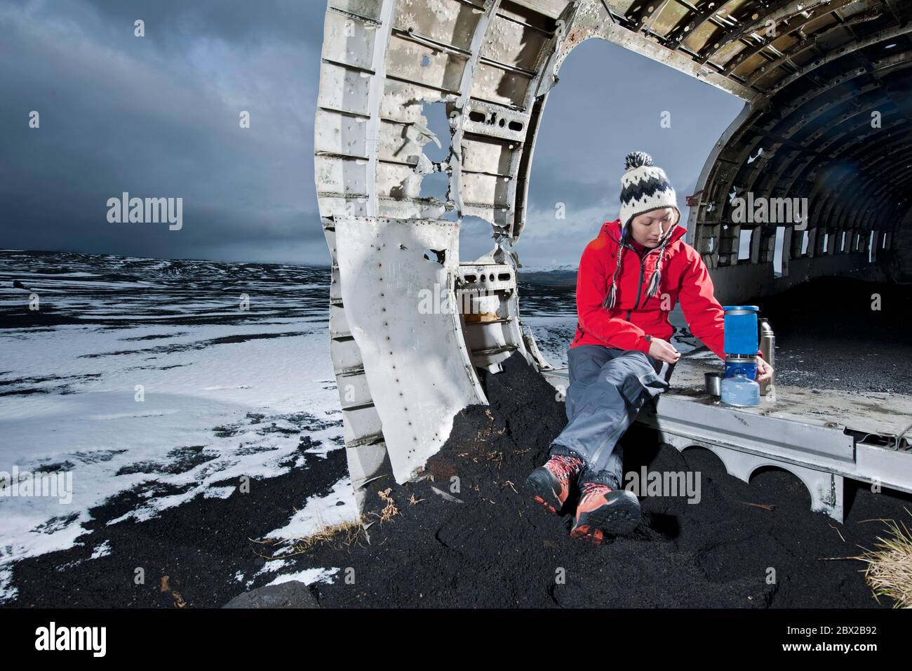 woman cooking meal on camping stove at famous plane wreck in Iceland