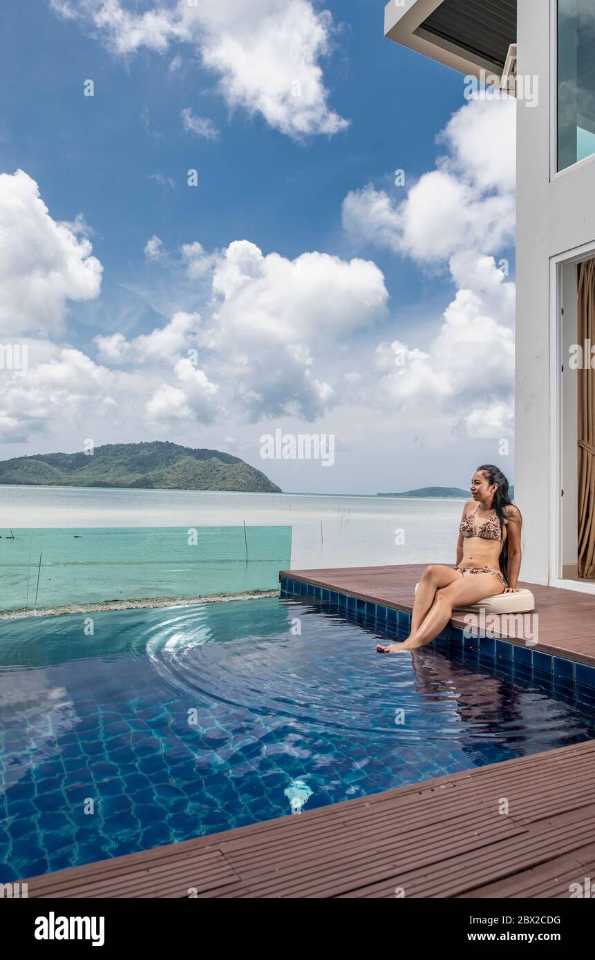 beautiful woman sitting by the pool at luxury villa in Phuket Stock Photo