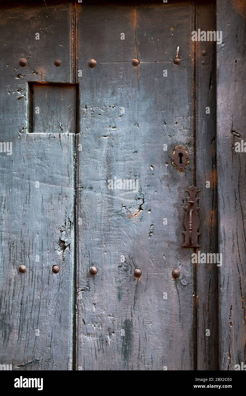 Old rustic wooden door with different layers of cracked paint in gray color Stock Photo